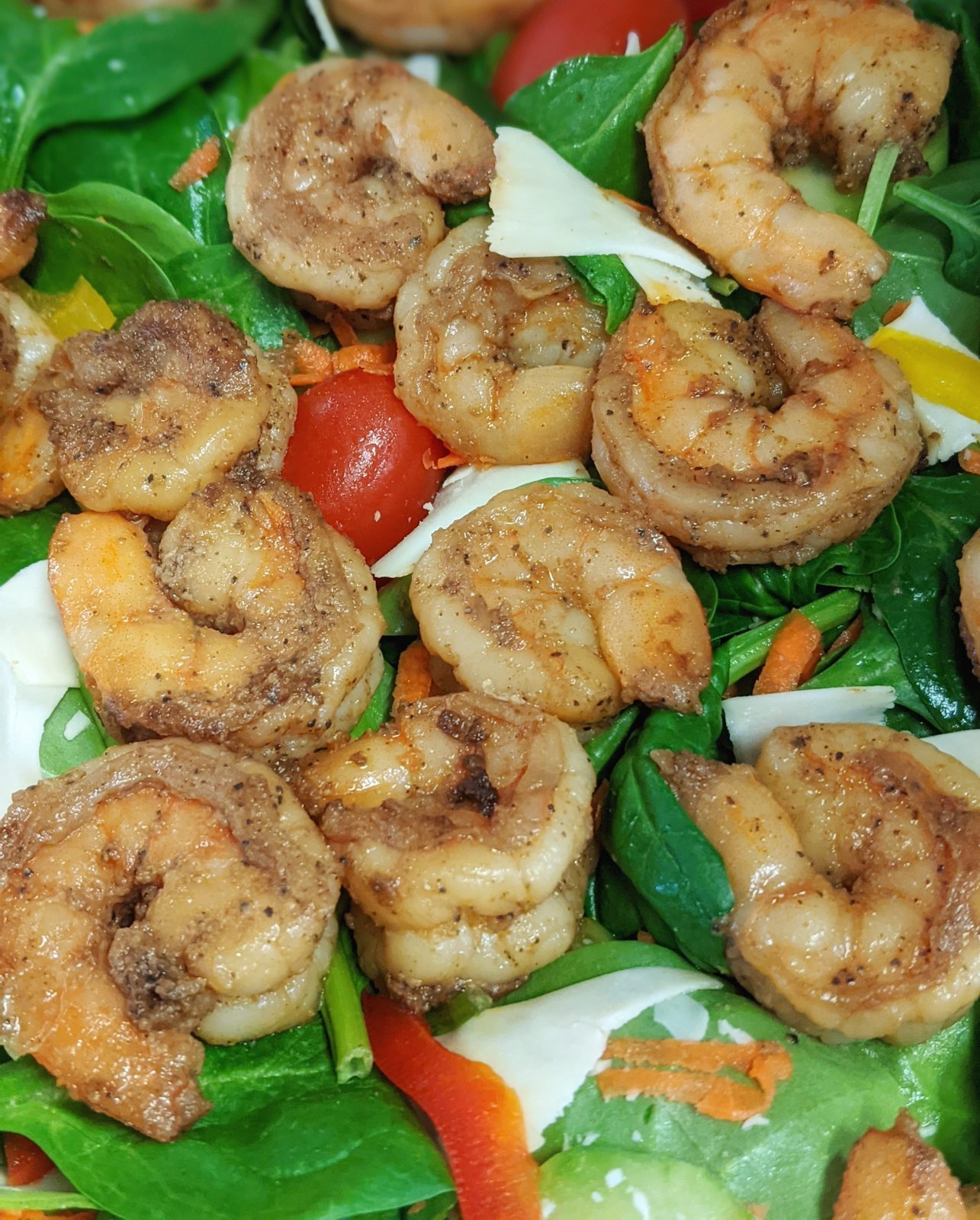 Blackened shrimp over greens with tomato and egg