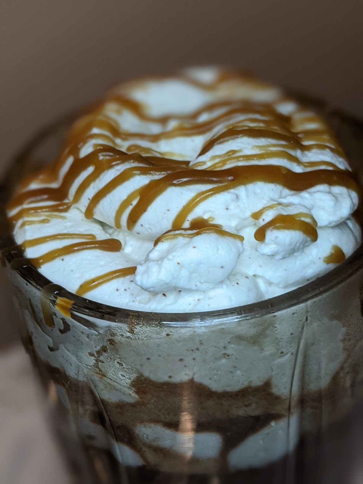 Whipped cream parfait drizzled with caramel in a glass