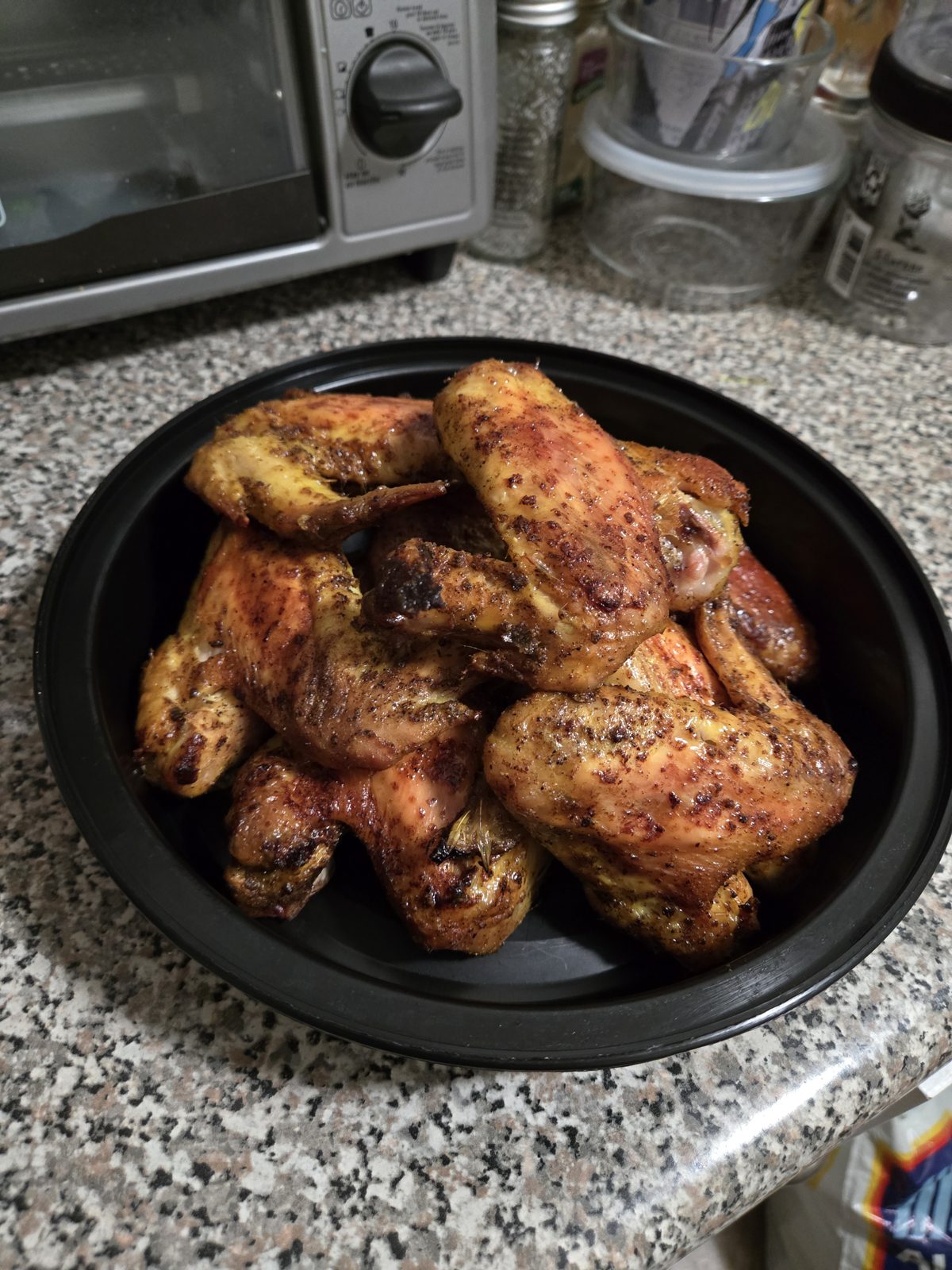 Seasoned baked chicken drumsticks on a black platter